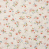 Ergobaby aura sustainably knitted wrap carrier showing a close up of the repeated bloom design on light pink fabric.