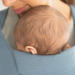 Close up of baby's head facing inwards in the Ergobaby Embrace Soft Knit Newborn Baby Carrier in Oxford Blue. 