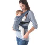 Woman wearing a grey top and her baby on her front facing inwards in the Ergobaby Embrace Soft Knit Newborn Baby Carrier in Oxford Blue. Side view, white background.