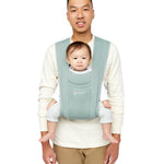 Man wearing a white top and his baby on his front facing outwards in the Ergobaby Embrace Soft Knit Newborn Baby Carrier in Oxford Blue. Front view white background.