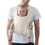 A man carrying a small baby in the Ergobaby soft knit newborn baby carrier, in cream.