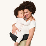 A woman carrying her baby on the Ergobaby Lift Hip Seat carrier, in Onyx Black. 