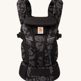 Ergobaby Omni Breeze Baby Carrier in omni breeze. A black coloured carrier with an abstract floral pattern. 