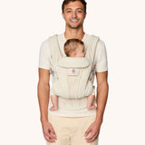 A man babywearing using the The Ergobaby Omni Deluxe Mesh baby carrier in Cloud White.