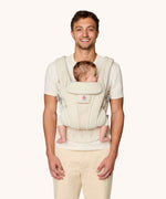 A man babywearing using the The Ergobaby Omni Deluxe Mesh baby carrier in Cloud White.