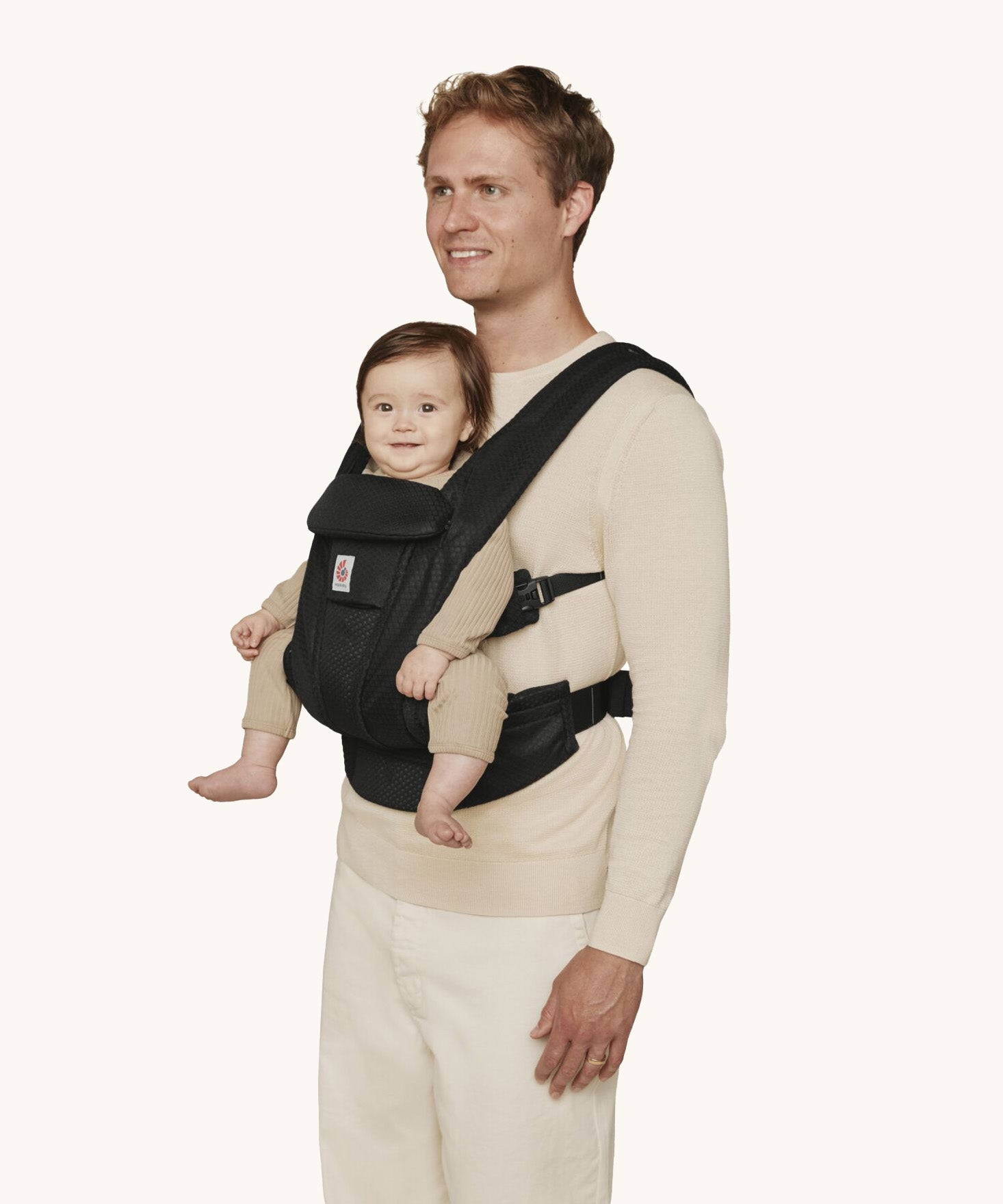 A man wearing the Ergobaby Omni Deluxe Mesh baby carrier in Onyx Black, with a little baby being carried facing outwards. 