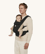 A man wearing the Ergobaby Omni Deluxe Mesh baby carrier in Onyx Black, with a little baby being carried facing outwards. 