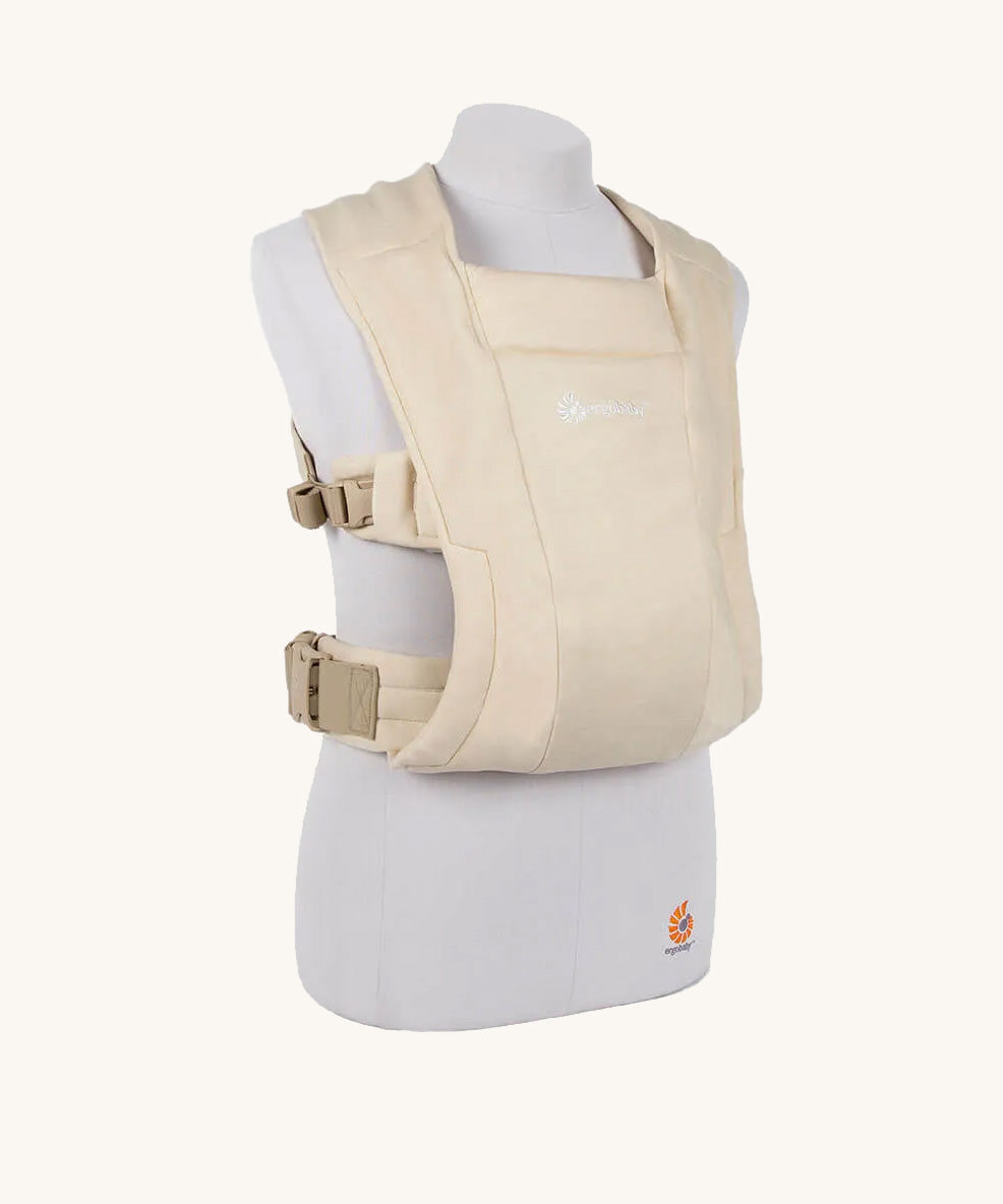 The Ergobaby Soft & Snug knit newborn baby carrier in a soft cream colour, from a side angle view.