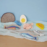 Pieces from the Erzi fish assortment wooden food play set placed on a blue coloured cloth in the Babipur playroom.