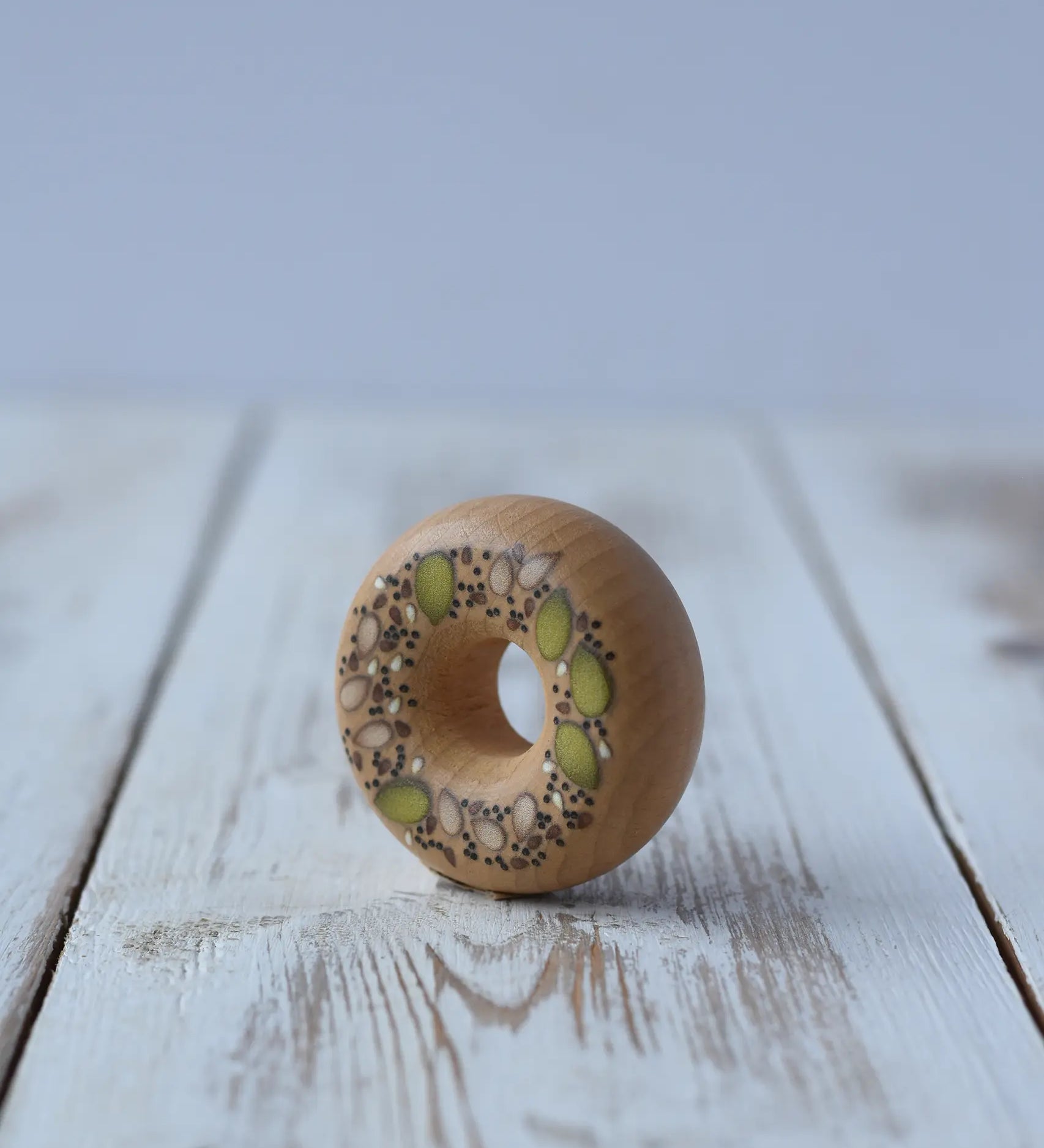 Erzi seeded bagel wooden play food placed on a wooden surface.