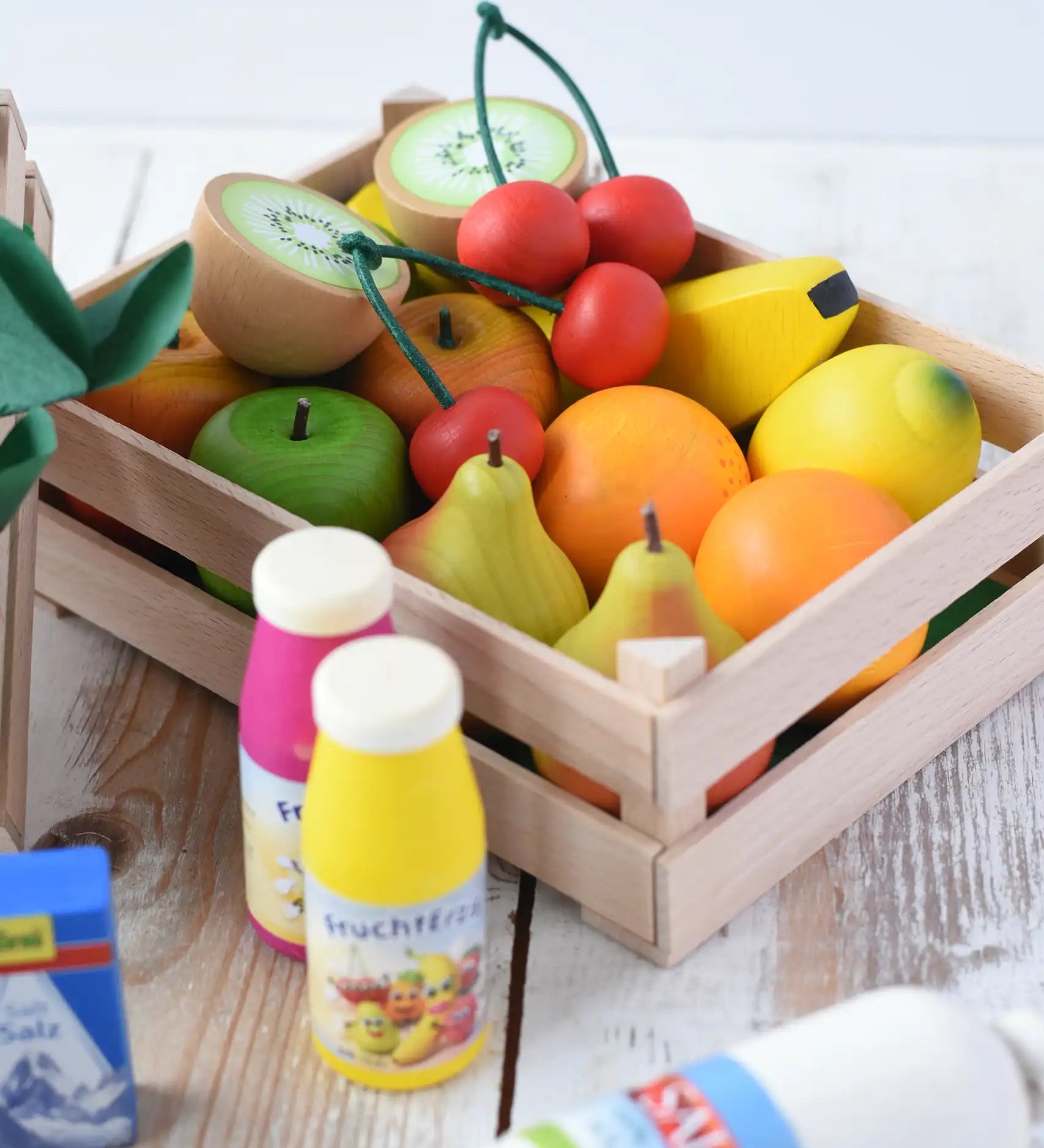 Erzi big wooden toy crate for fruit filled with wooden fruit play food including cherries, kiwis, bananas, apples, lemons and oranges.