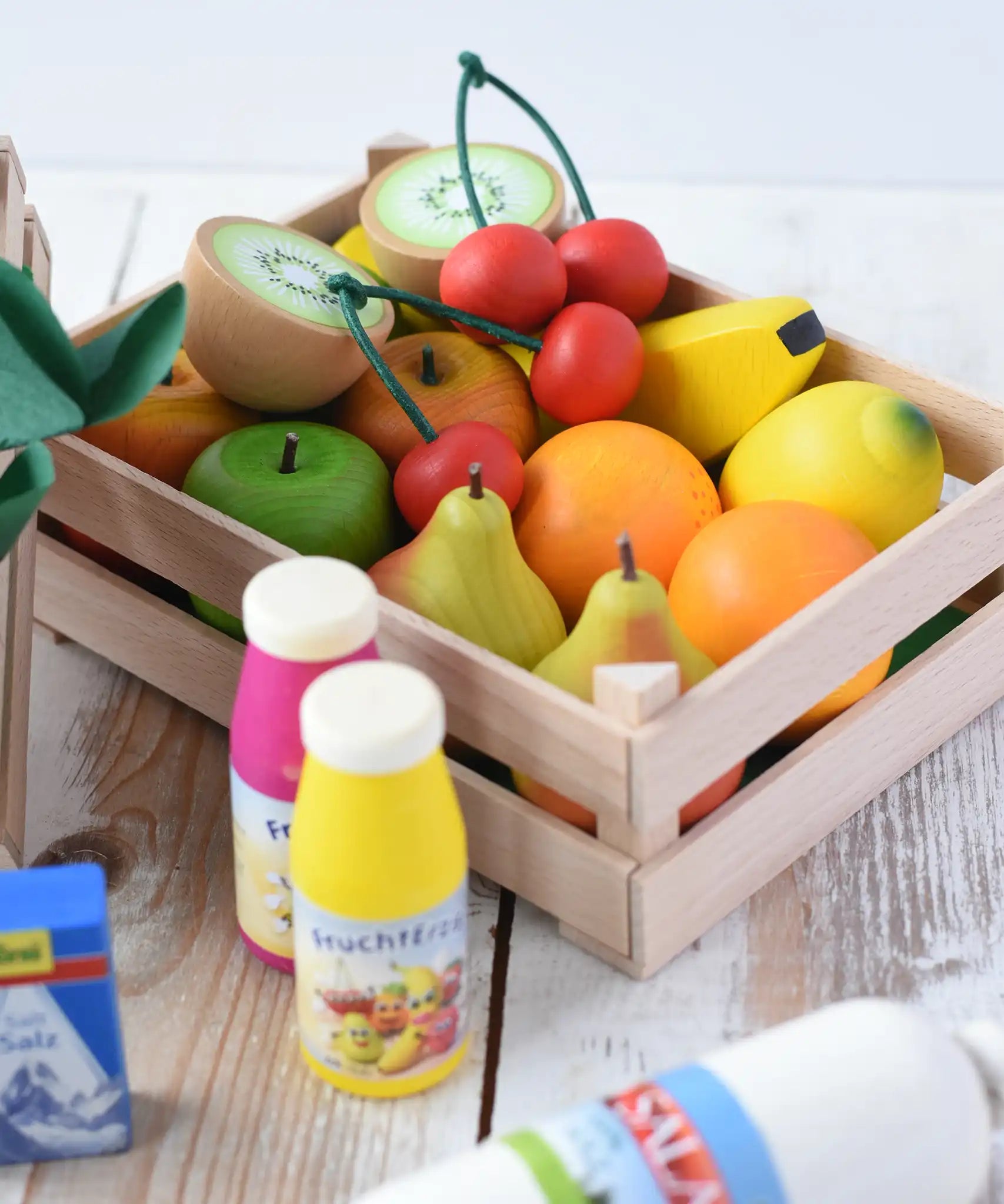 Erzi big wooden toy crate for fruit filled with wooden fruit play food including cherries, kiwis, bananas, apples, lemons and oranges.