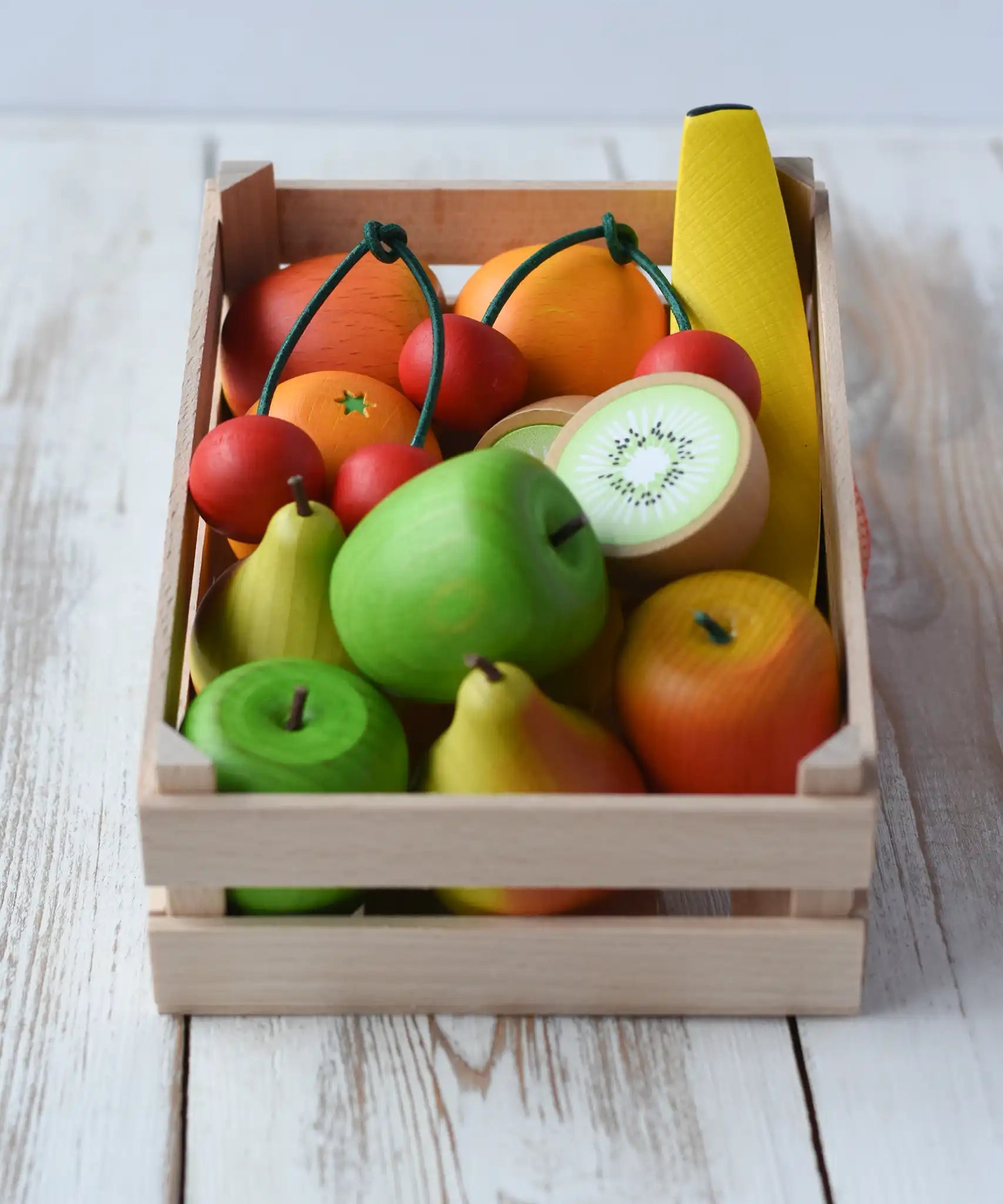 Erzi big wooden toy crate for fruit filled with wooden fruit play food including cherries, kiwis, bananas, apples, lemons and oranges.