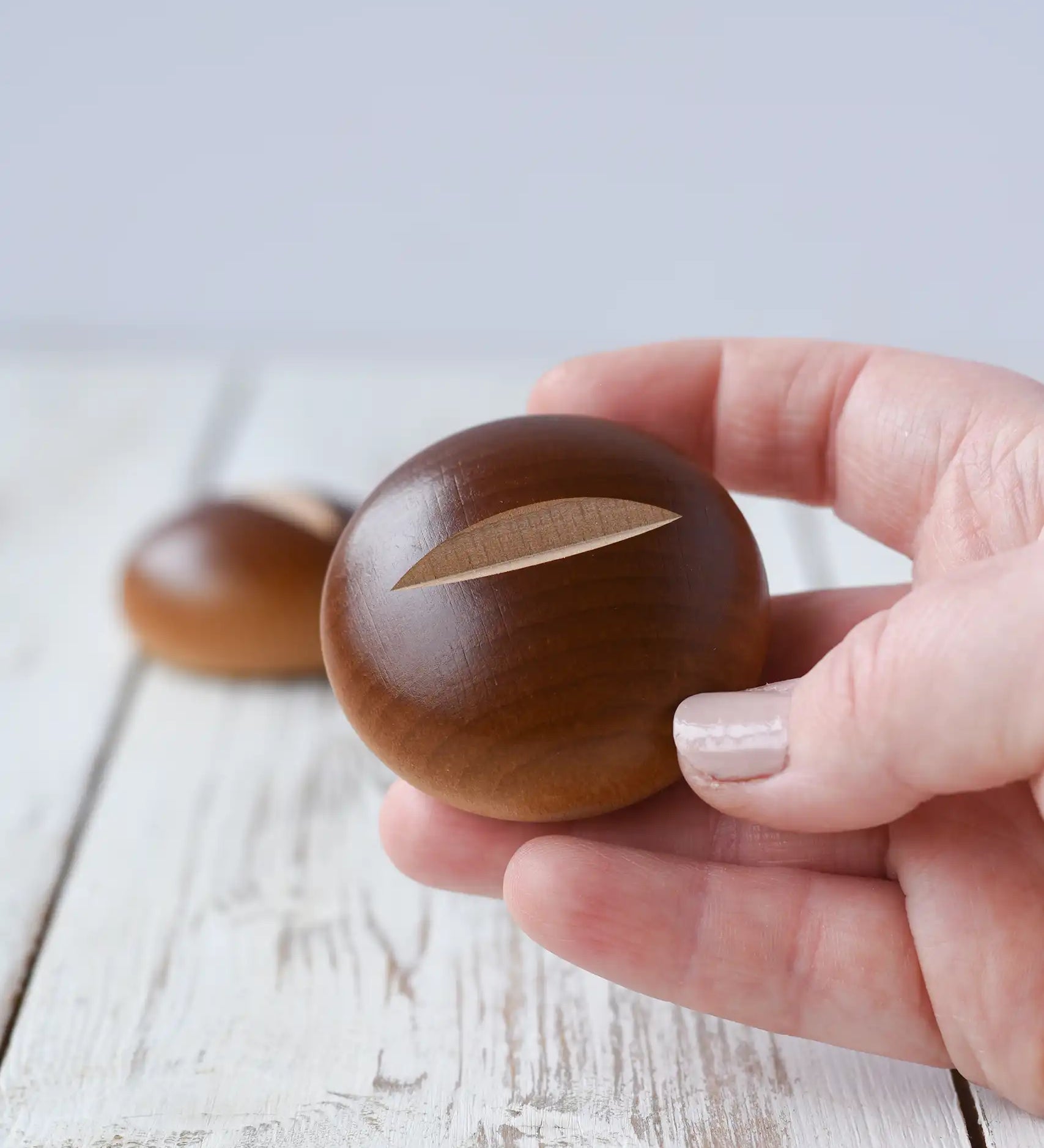 Erzi bread roll wooden play food in an adult's hand. 