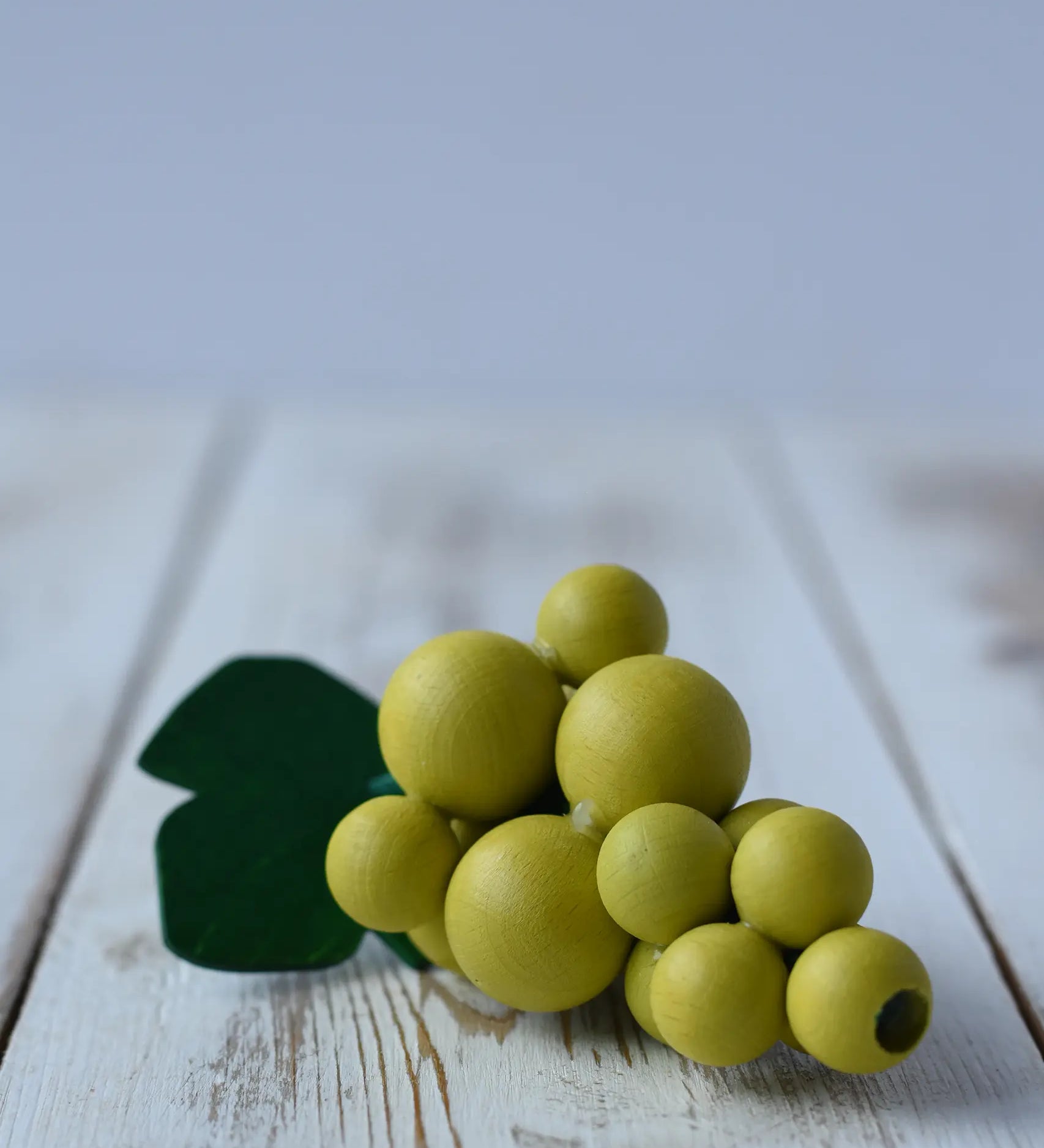 Erzi Bunch Of Green Grapes Wooden Play Food on a wooden surface.