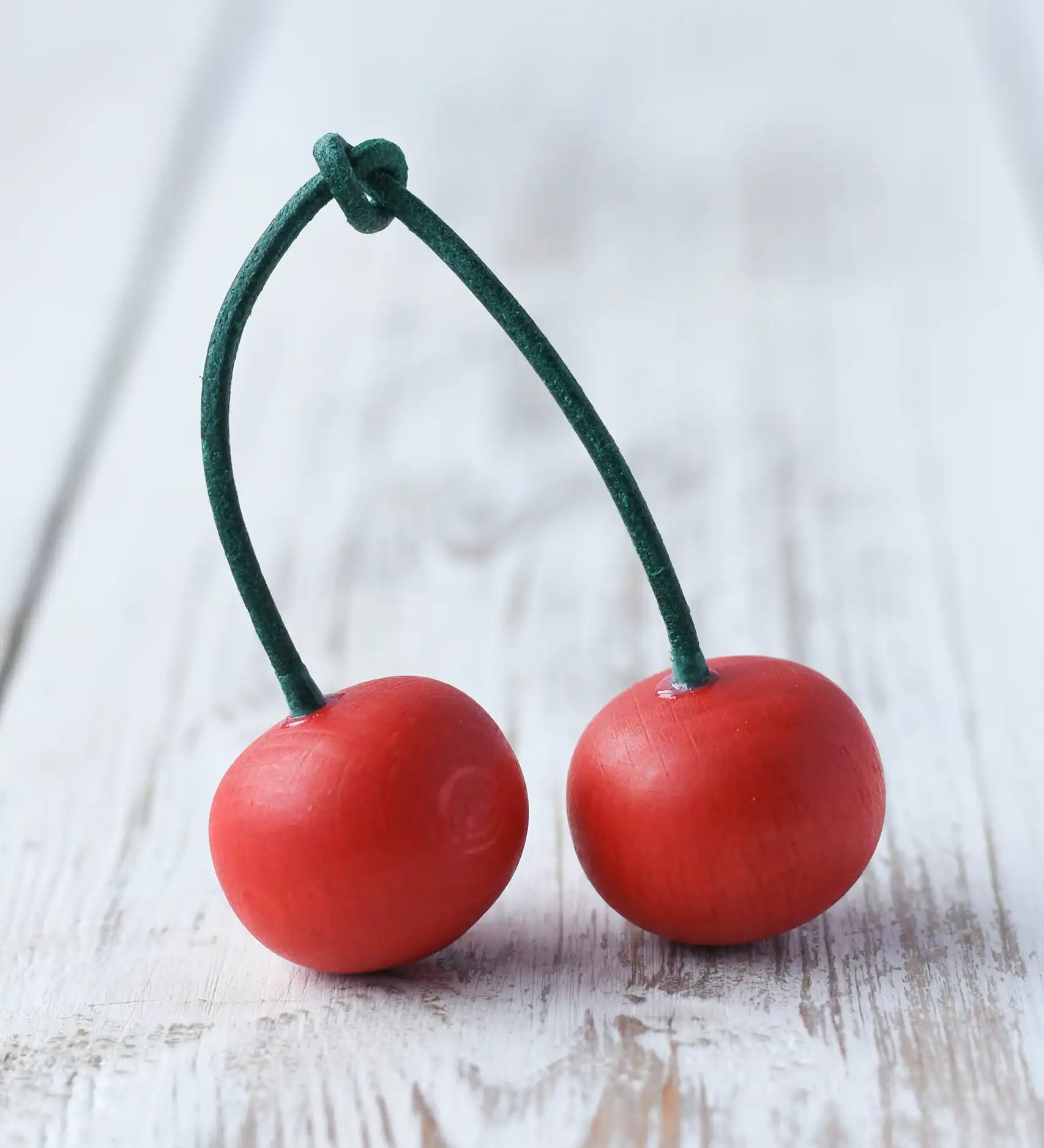 Erzi pair of cherries wooden play food placed on a wooden surface. Red fruits on a green stem.