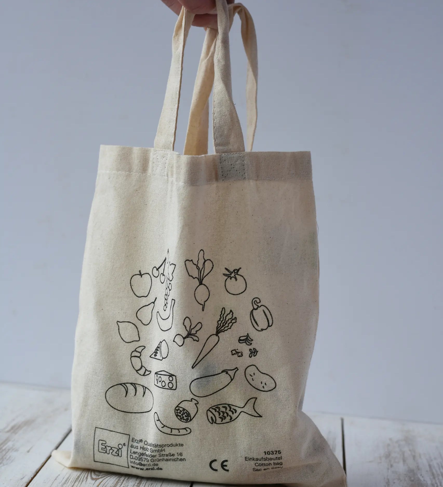Erzi cotton toy shopping bag being placed down on a wooden surface.