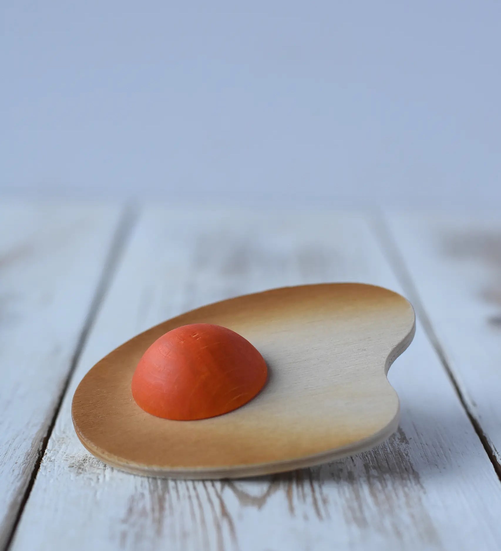 Erzi fried egg sunny-side up wooden play food placed on a wooden surface.