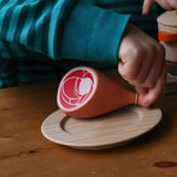 Erzi Gammon joint Wooden Play Food placed on a wooden toy place, child's hand picking up the meat. 