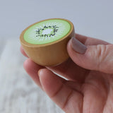 Erzi half kiwi fruit wooden play food in an adult's hand.