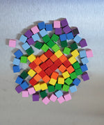 A colorful set of small Erzi wooden magnetic blocks from the pixelino set on a Triclimb Biri board