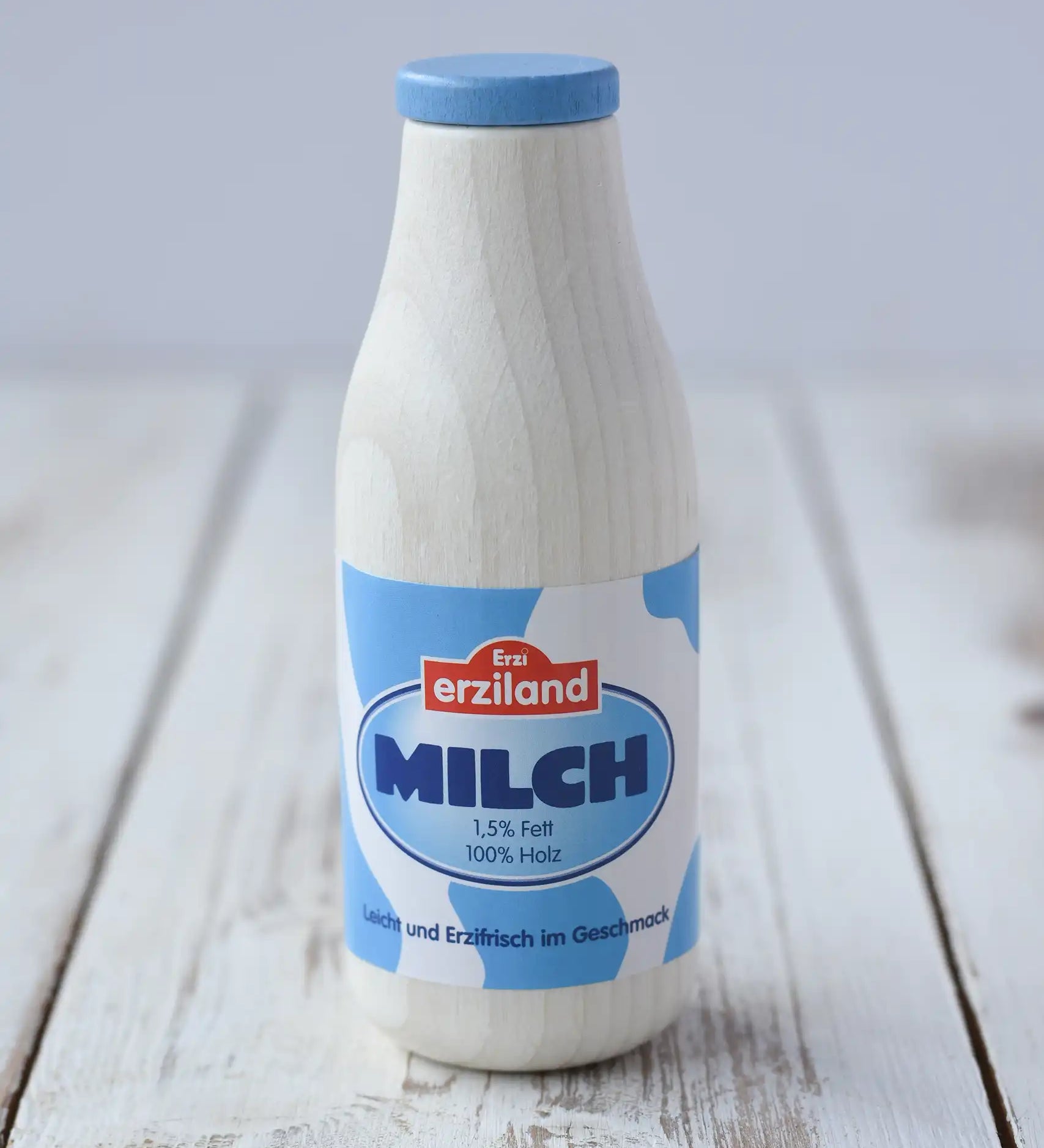 Erzi toy milk wooden play food placed on a wooden surface. 