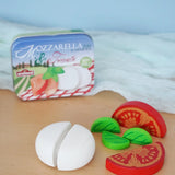 Erzi mozzarella and tomato wooden play food set placed next to their metal storage tin in the Babipur playroom.