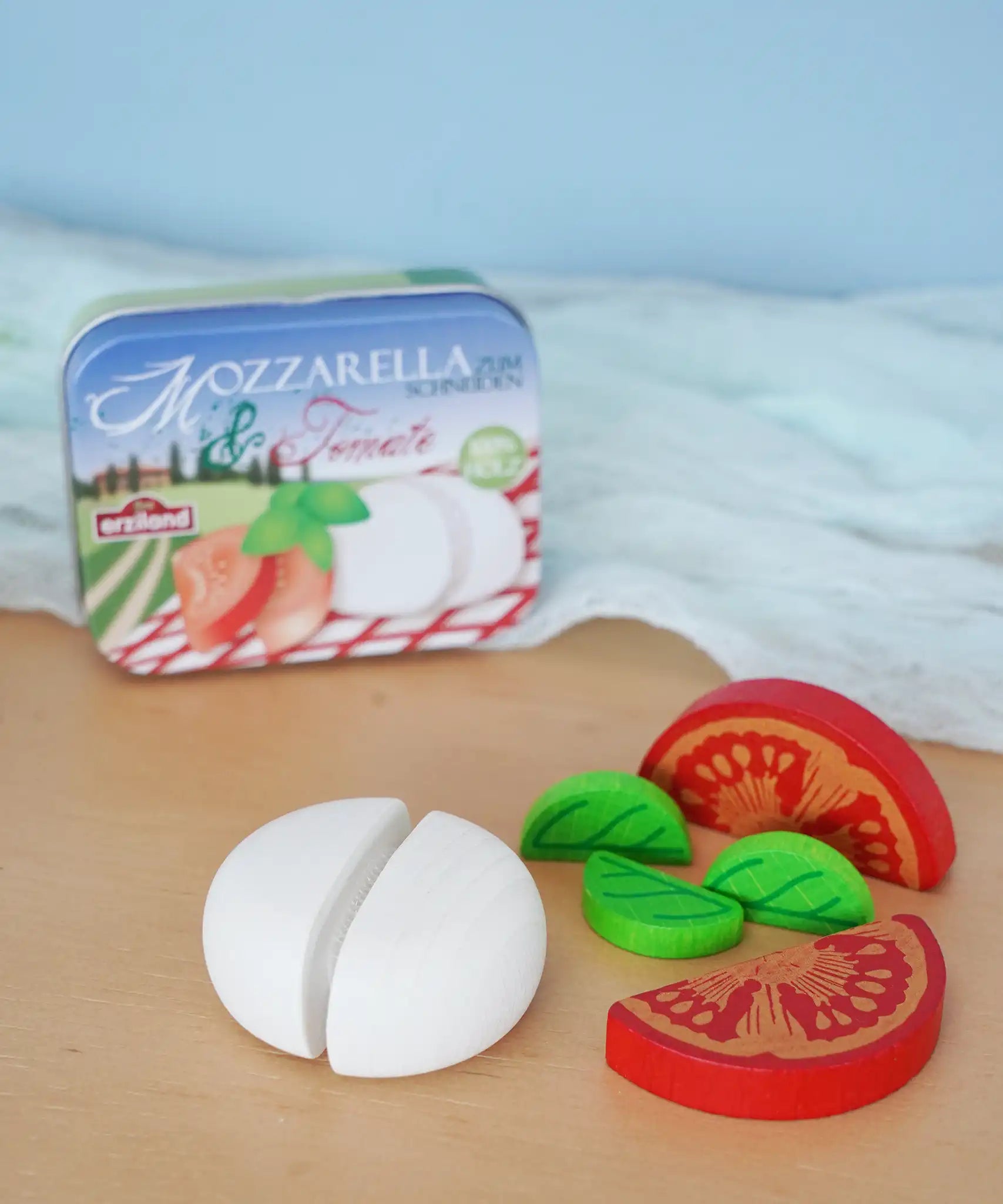 Erzi mozzarella and tomato wooden play food set placed next to their metal storage tin in the Babipur playroom.