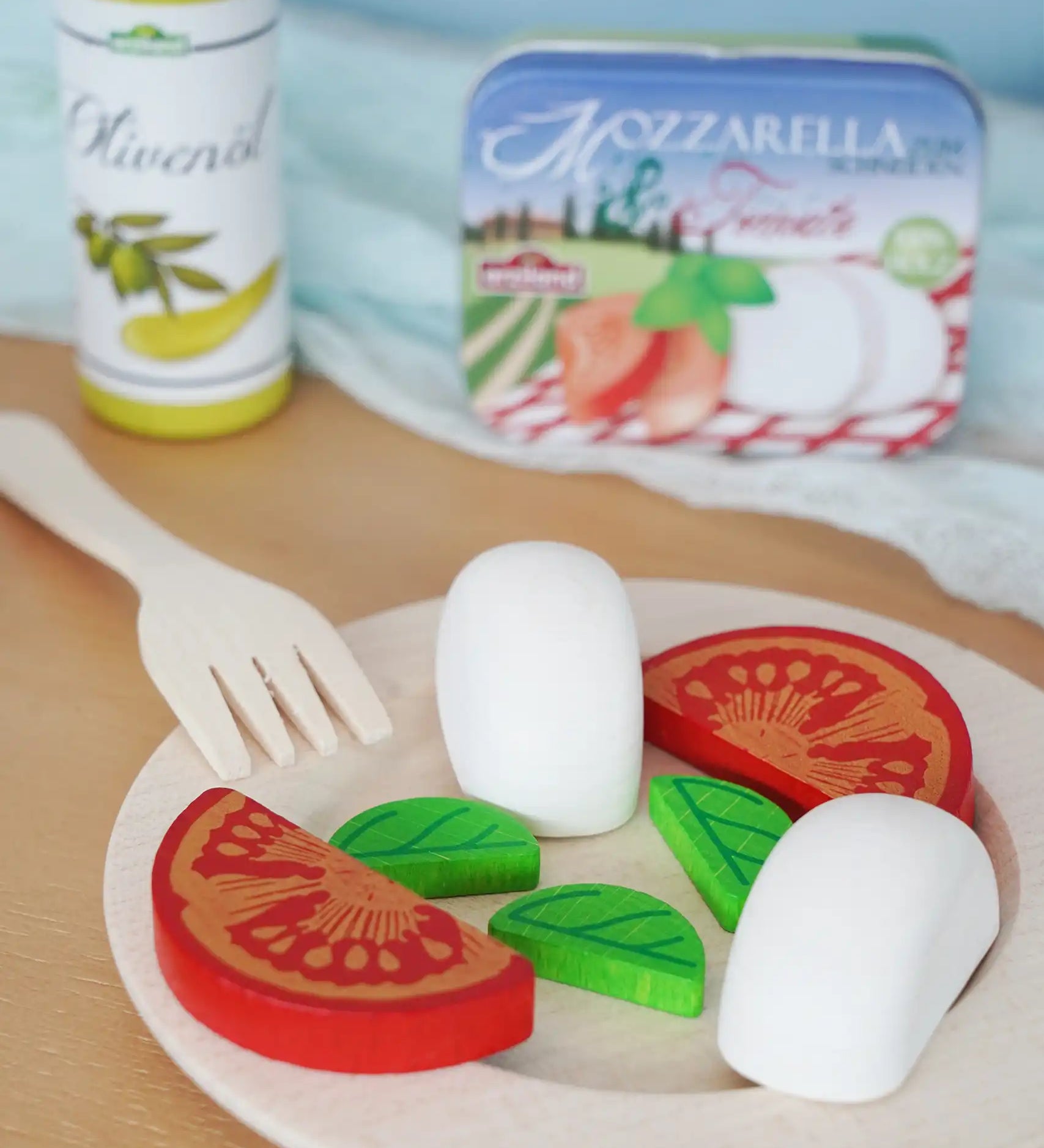 Erzi mozzarella and tomato in a metal tin wooden play food set placed on a wooden plate in the Babipur playroom.