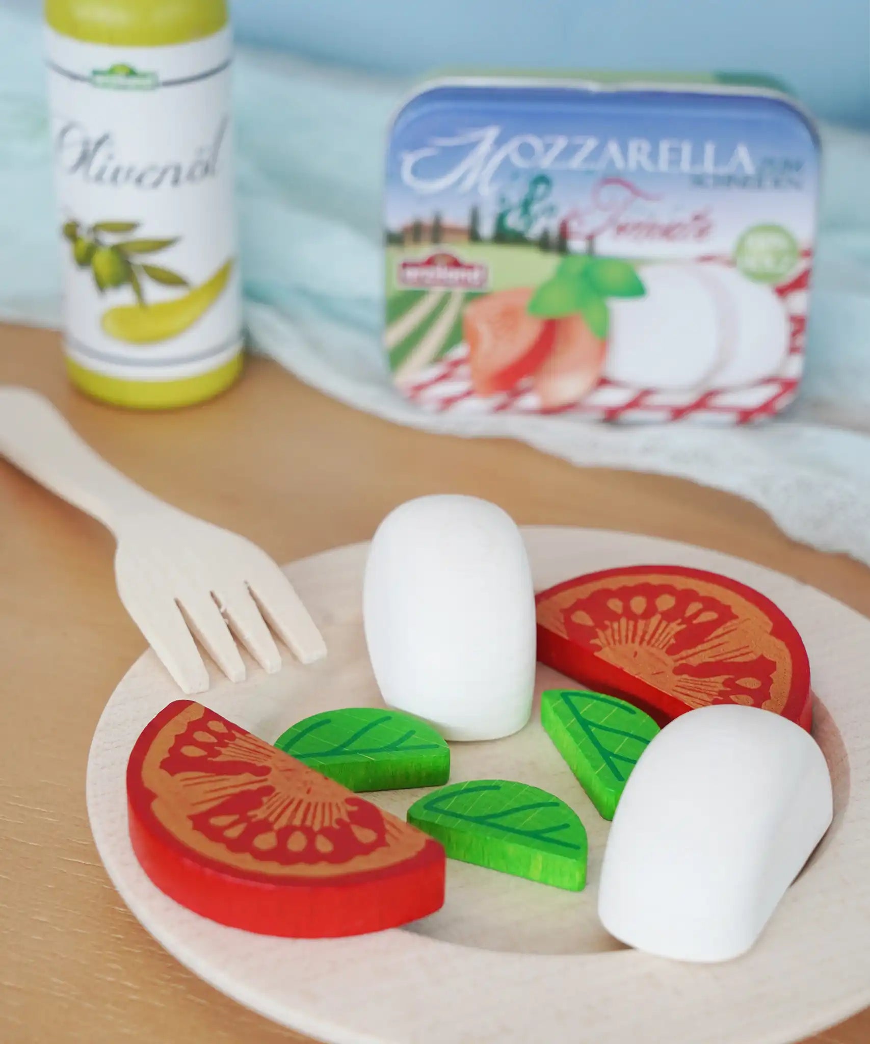 Erzi mozzarella and tomato in a metal tin wooden play food set placed on a wooden plate in the Babipur playroom.