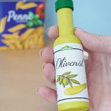 Erzi olive oil bottle wooden play food in an adult's hand in the Babipur playroom.
