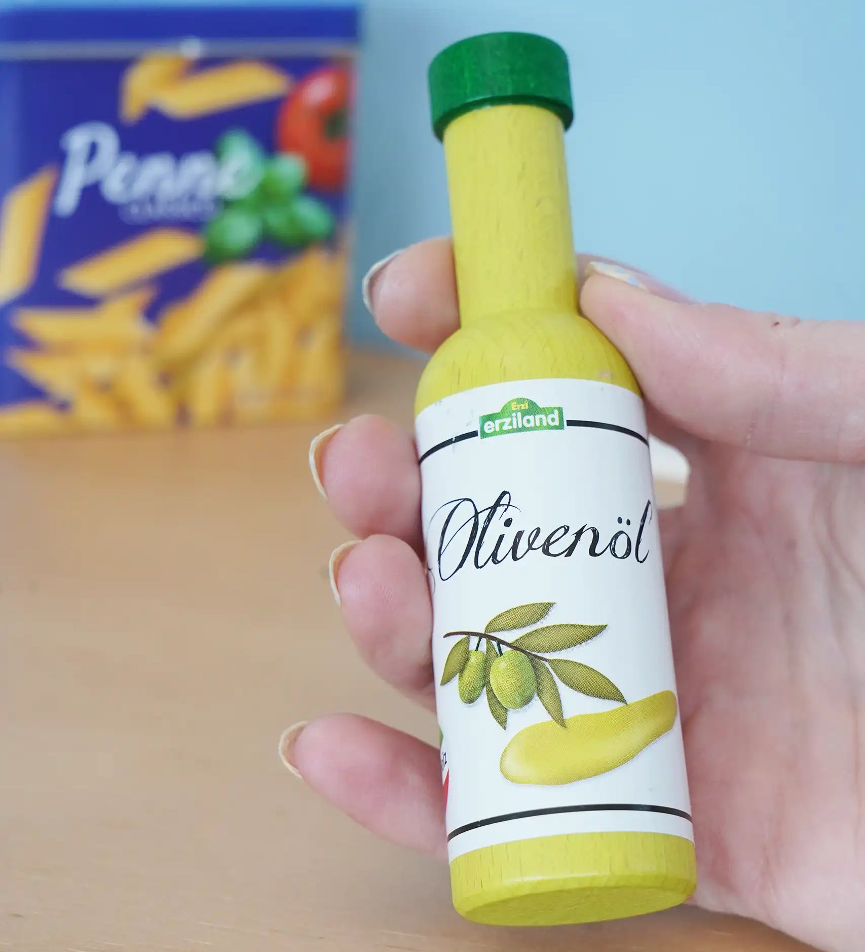 Erzi olive oil bottle wooden play food in an adult's hand in the Babipur playroom.