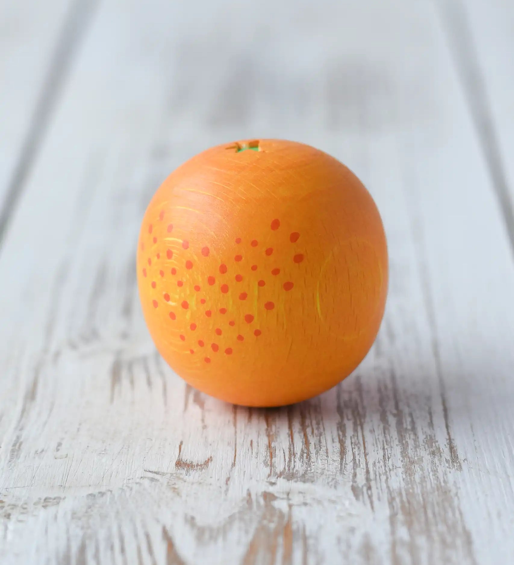 Erzi orange wooden play food placed on a wooden surface. 