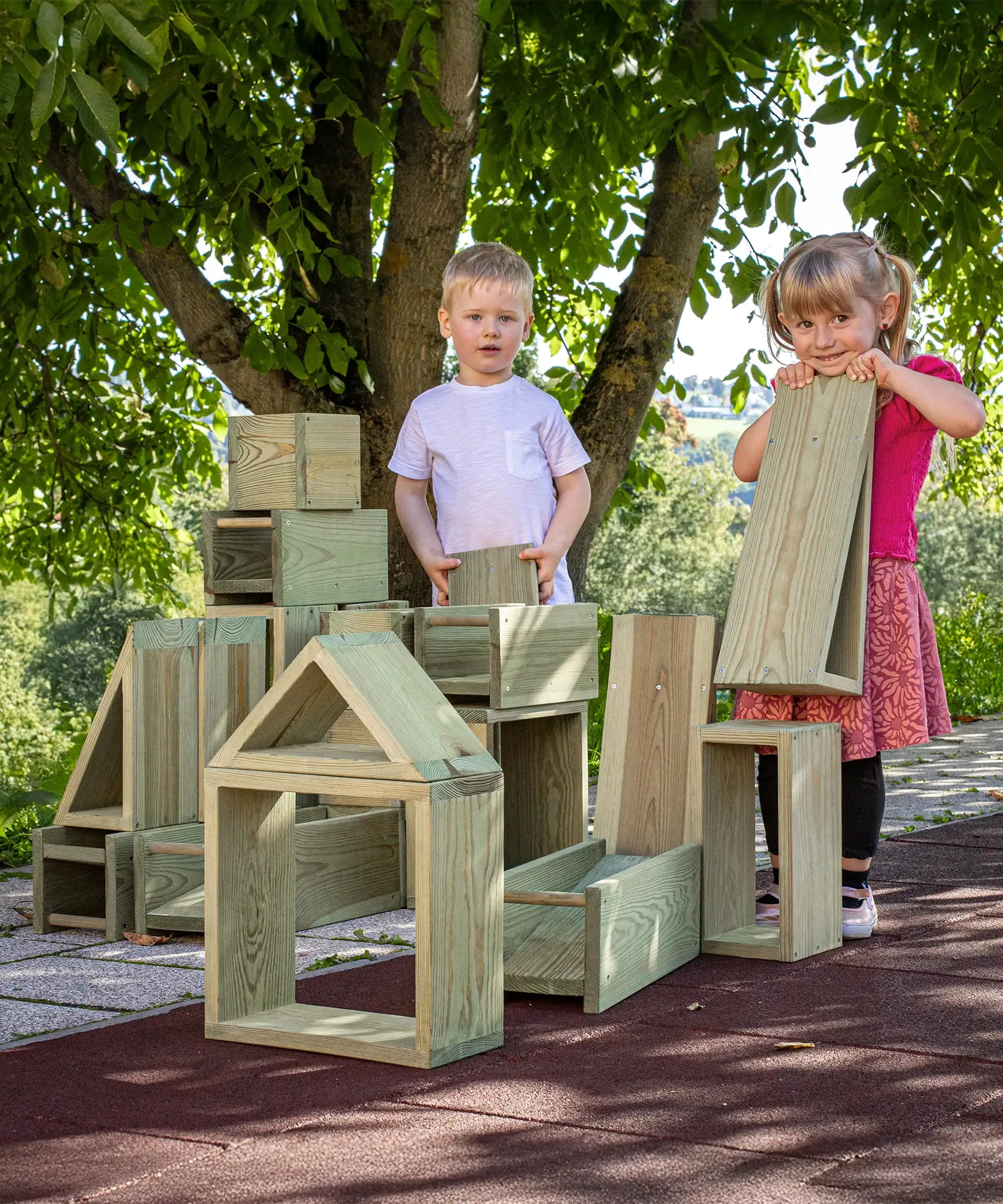 Children playing with the Erzi wooden outdoor building block set. Large blocks in various sizes.