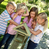 Children playing with the Erzi wooden outdoor building block set. They are stacking the large blocks on top of each other.