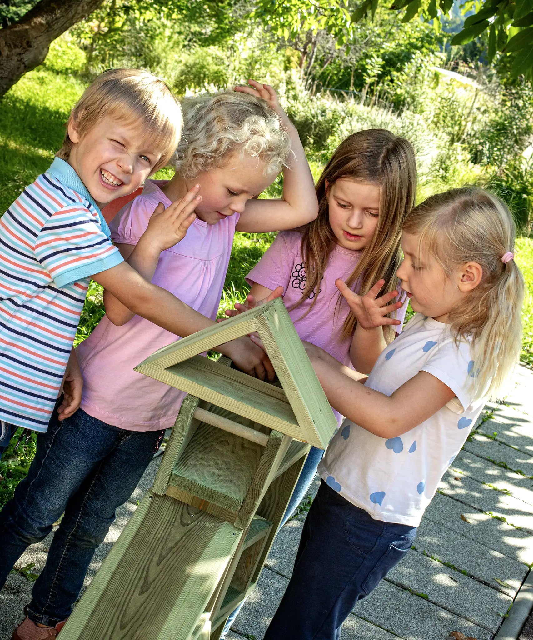 Children playing with the Erzi wooden outdoor building block set. They are stacking the large blocks on top of each other.