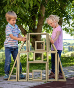 Children playing with the Erzi wooden outdoor building block set. They are stacking the large blocks on top of each other.