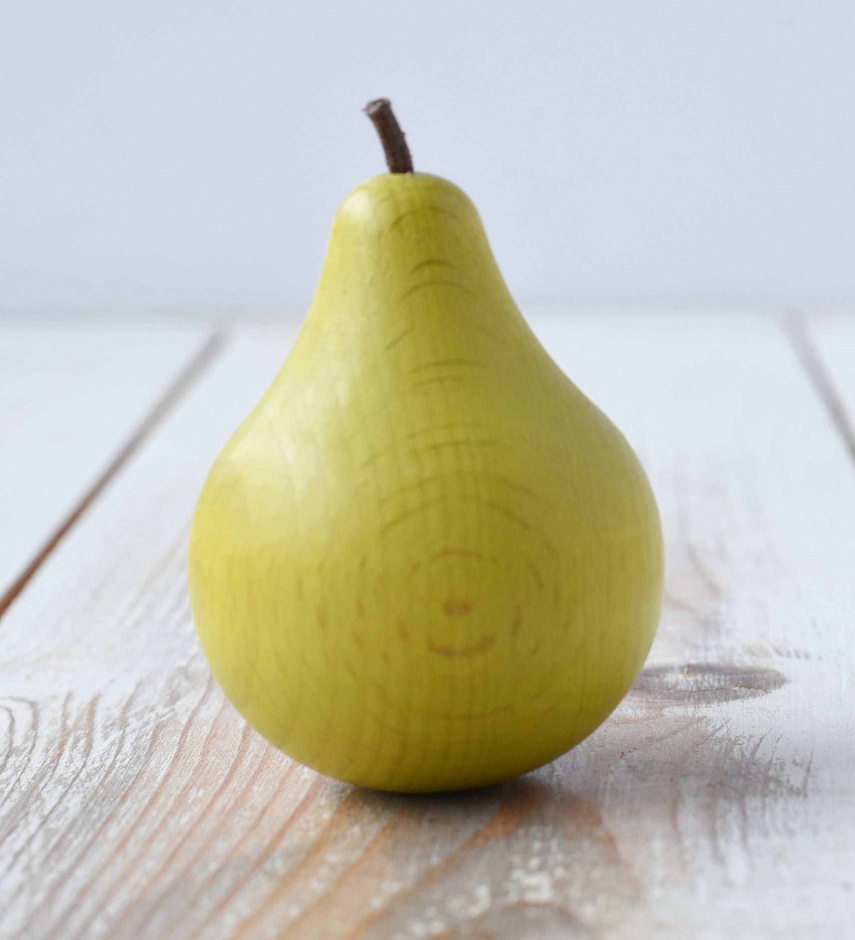 Erzi green pear wooden play food placed on a wooden surface.