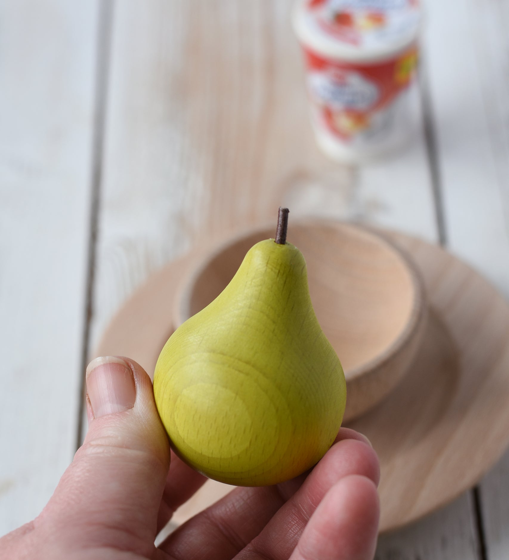 Erzi green pear wooden play food in an adult's hand