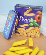 Erzi children's wooden play food penne pasta laid out next to the open metal tin they come in in the Babipur playroom.