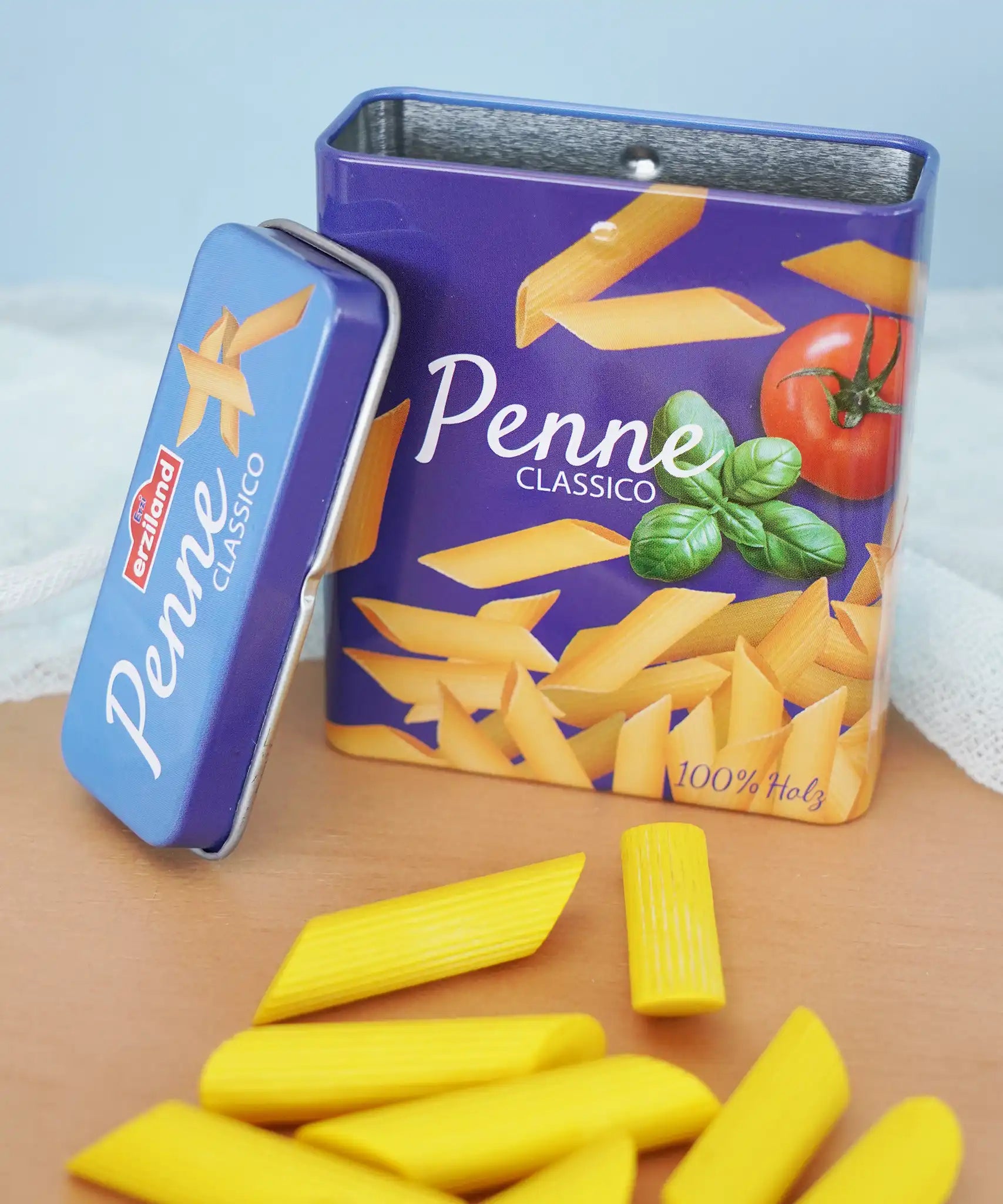 Erzi children's wooden play food penne pasta laid out next to the open metal tin they come in in the Babipur playroom.