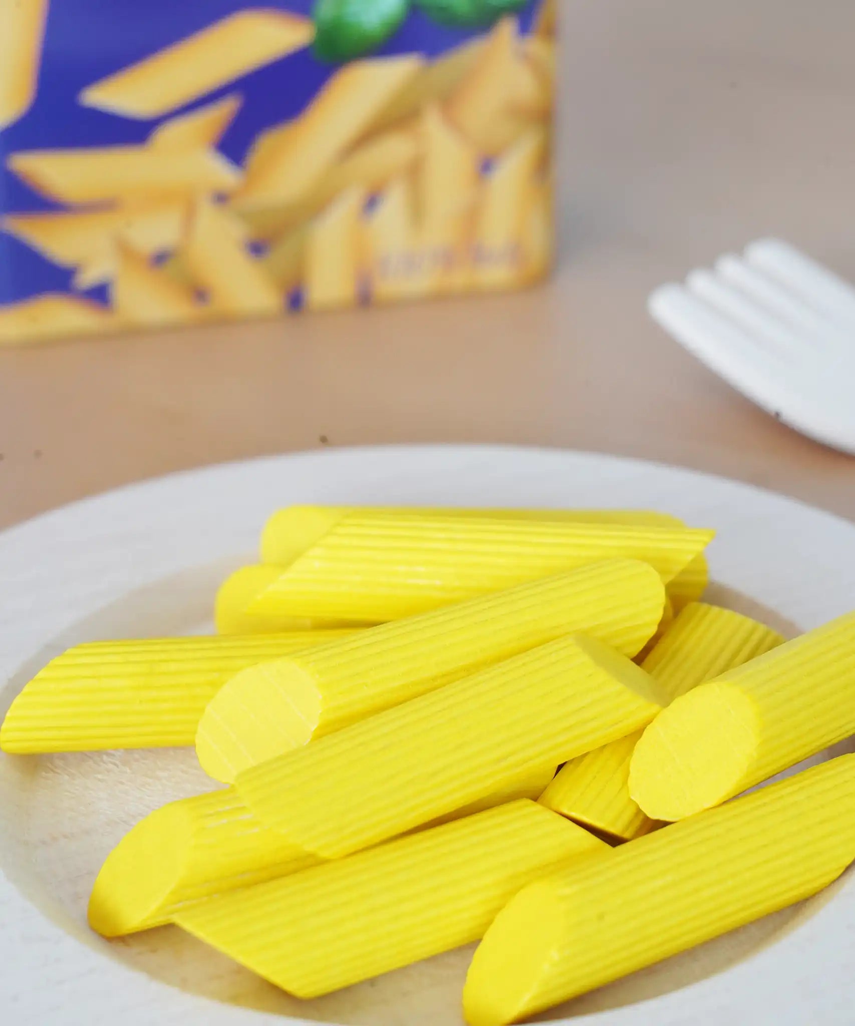 Erzi wooden play food penne pasta placed on a plate in the Babipur playroom.
