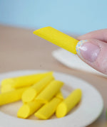 Adult hand holding a loose Erzi penne pasta piece showing scale