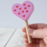 Erzi pink raspberry heart shaped ice lolly wooden play food toy in an adult's hand.
