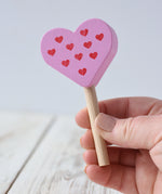 Erzi pink raspberry heart shaped ice lolly wooden play food toy in an adult's hand.
