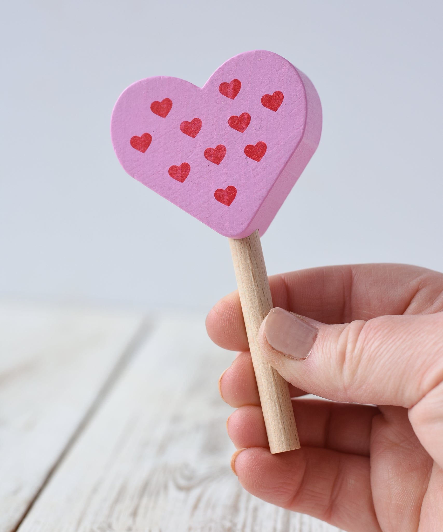 Erzi pink raspberry heart shaped ice lolly wooden play food toy in an adult's hand.

