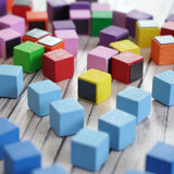 A collection of small, colorful Erzi wooden blocks with some showing the magnetic piece on the underside