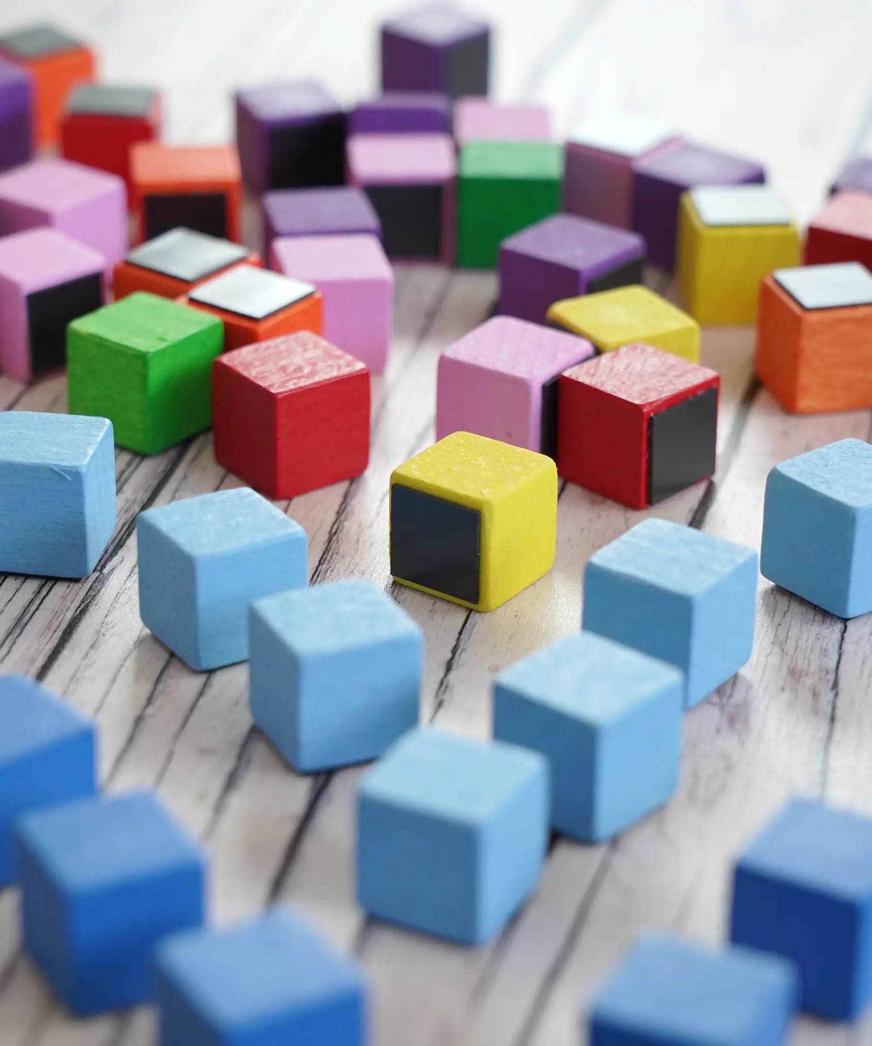 A collection of small, colorful Erzi wooden blocks with some showing the magnetic piece on the underside