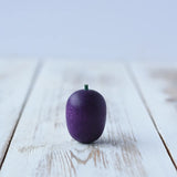 Erzi Plum Wooden Play Food placed on a wooden board. Purple plum with a small green stock.