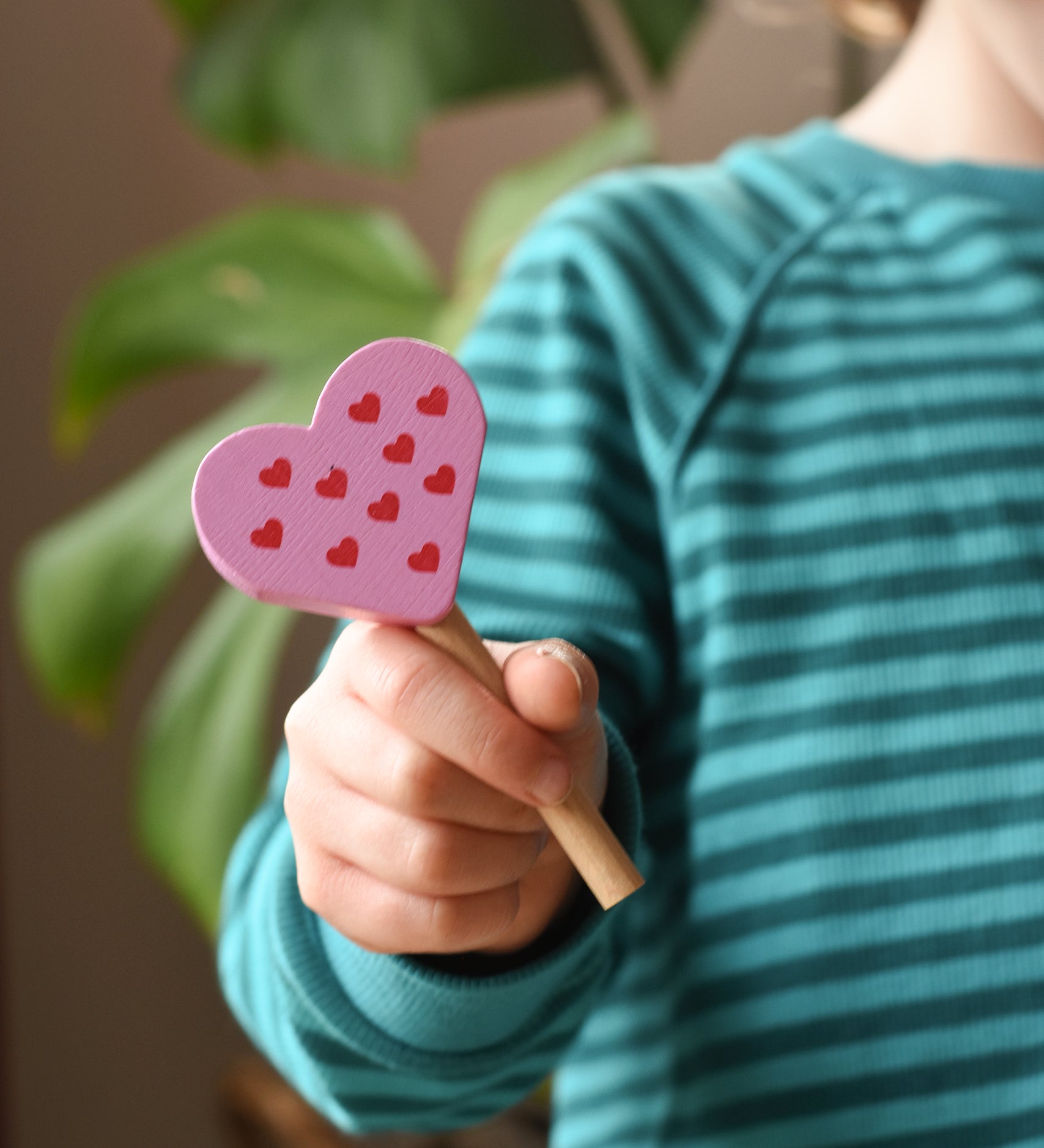 Erzi pink raspberry heart shaped ice lolly wooden play food in a child's hand.
